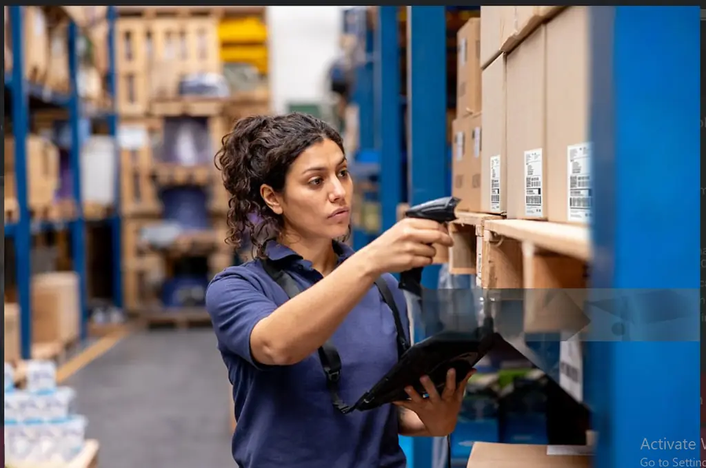 Warehouse specialist scanning inventory barcodes on high racking shelves with a handheld scanner